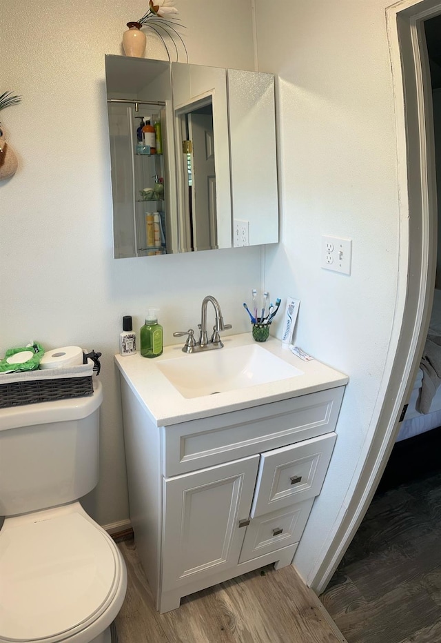 bathroom with toilet, wood finished floors, and vanity