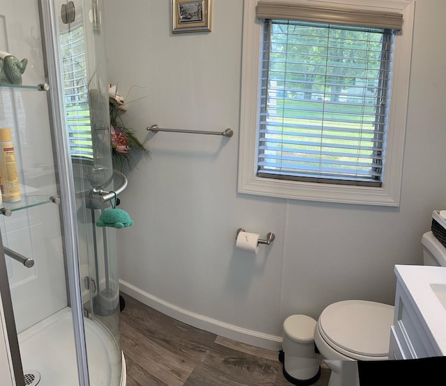 full bathroom featuring toilet, a stall shower, wood finished floors, baseboards, and vanity