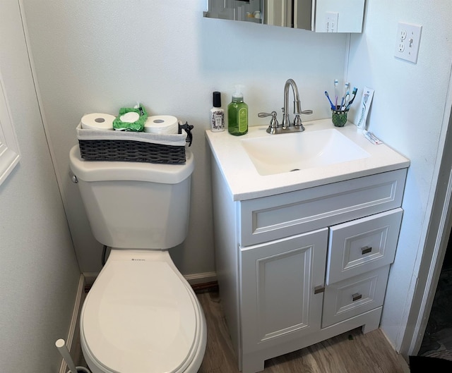 half bathroom featuring toilet, wood finished floors, and vanity