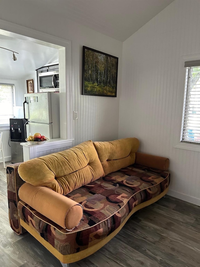 living area with baseboards, lofted ceiling, and wood finished floors