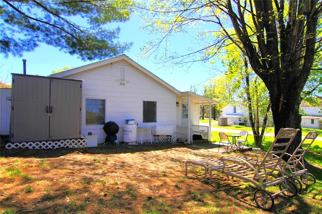 back of house featuring a storage shed, a lawn, an outbuilding, and a patio area
