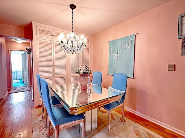 dining space featuring baseboards, light wood-type flooring, and a chandelier