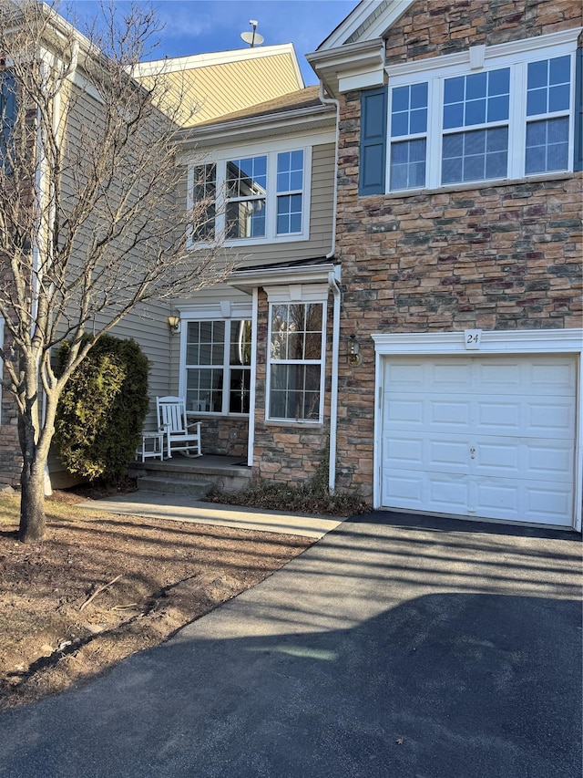 view of front of property with stone siding, an attached garage, and driveway