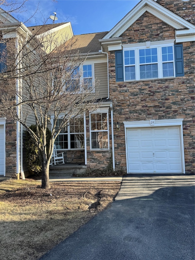 view of front of house with aphalt driveway, stone siding, a porch, and a garage