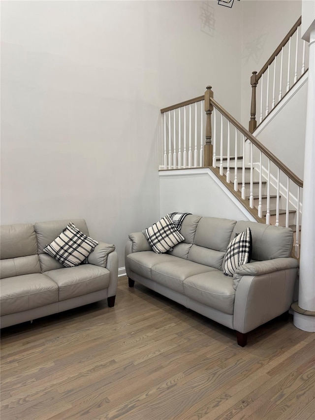 living area featuring stairway, baseboards, a towering ceiling, and wood finished floors