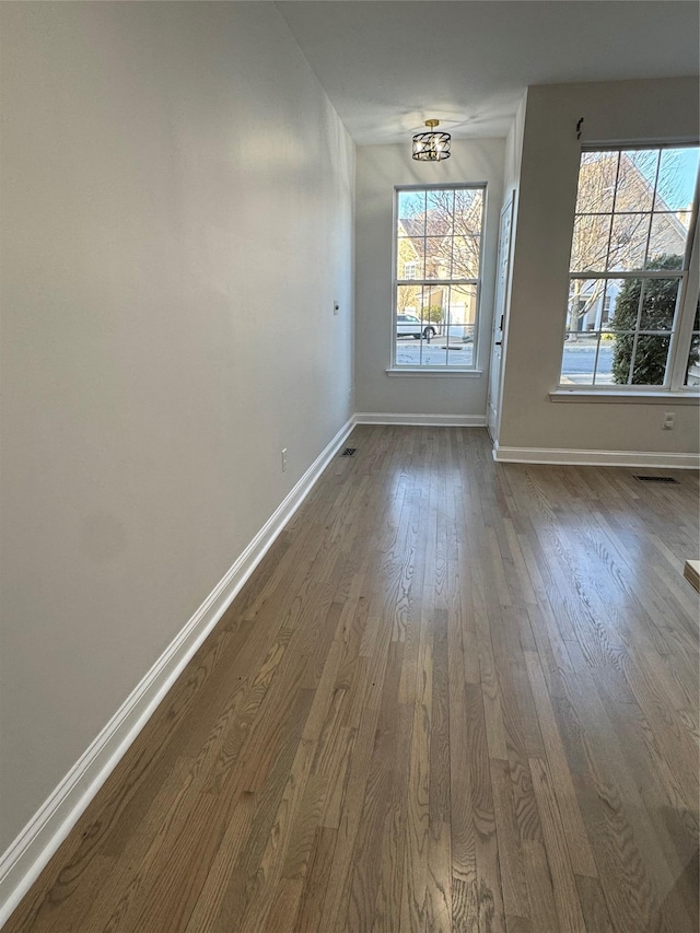 unfurnished dining area with visible vents, baseboards, and dark wood-style flooring