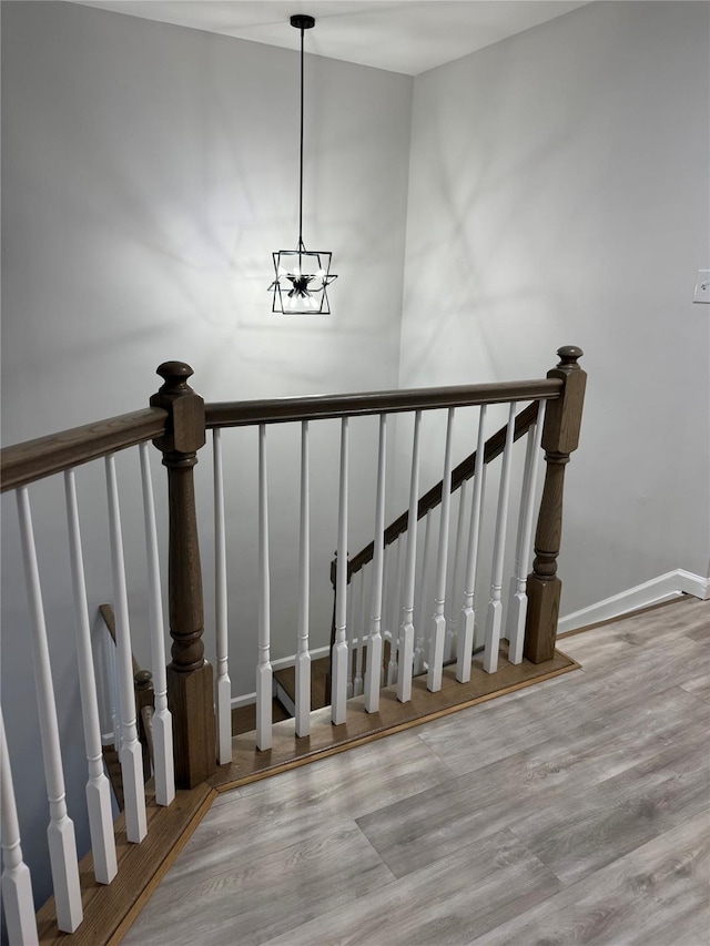 stairs with a chandelier, baseboards, and wood finished floors