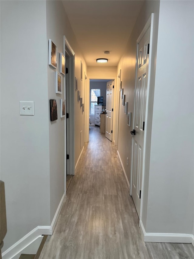 hall with light wood-style flooring and baseboards