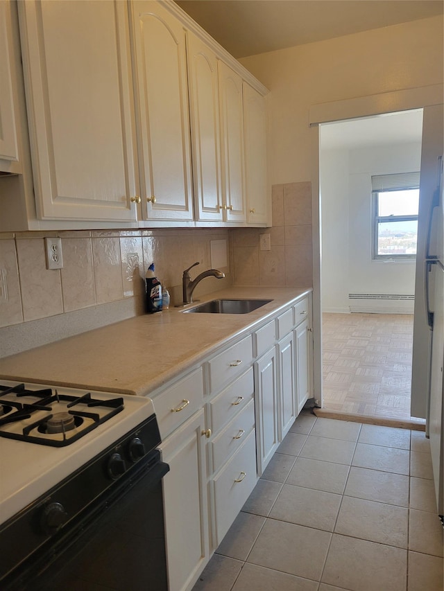 kitchen with light countertops, backsplash, range with gas stovetop, and a sink