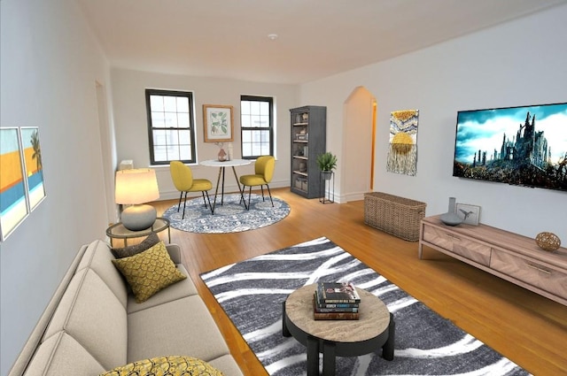 living area featuring wood finished floors, arched walkways, and baseboards