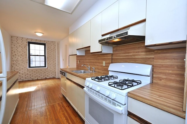kitchen featuring brick wall, white range with gas cooktop, a sink, white cabinets, and under cabinet range hood