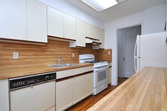 kitchen with white appliances, a sink, white cabinets, under cabinet range hood, and tasteful backsplash