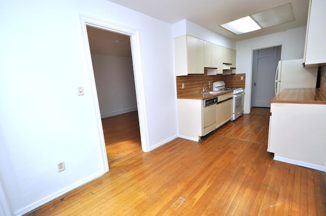 kitchen featuring a sink, white cabinetry, white appliances, light wood finished floors, and decorative backsplash