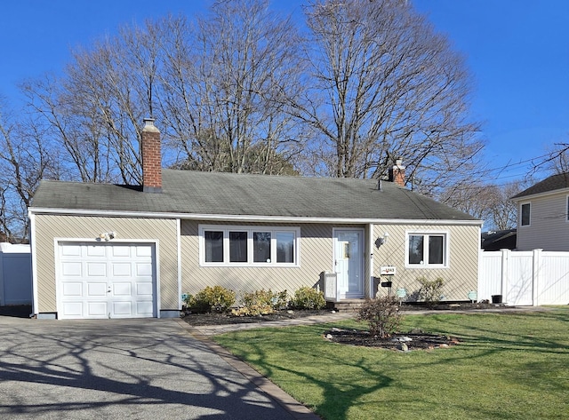 view of front of property featuring a front lawn, fence, aphalt driveway, a chimney, and a garage