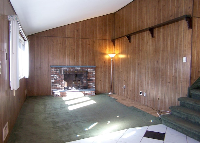 unfurnished living room with lofted ceiling, wooden walls, and a fireplace