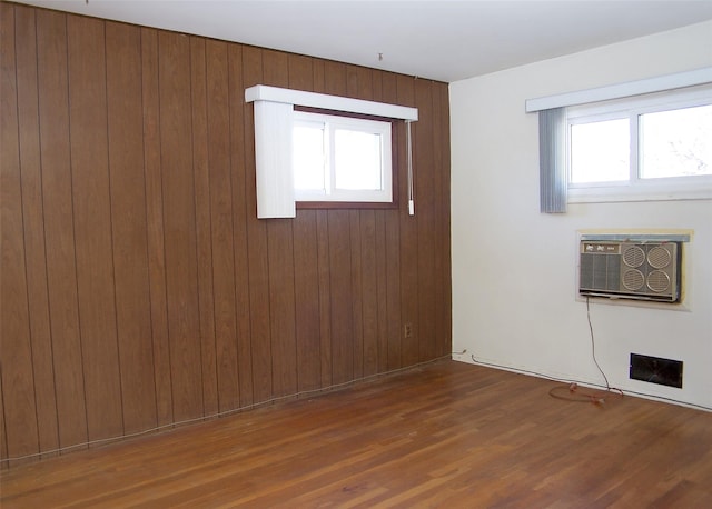 empty room with wood walls, a wall mounted air conditioner, and dark wood-type flooring