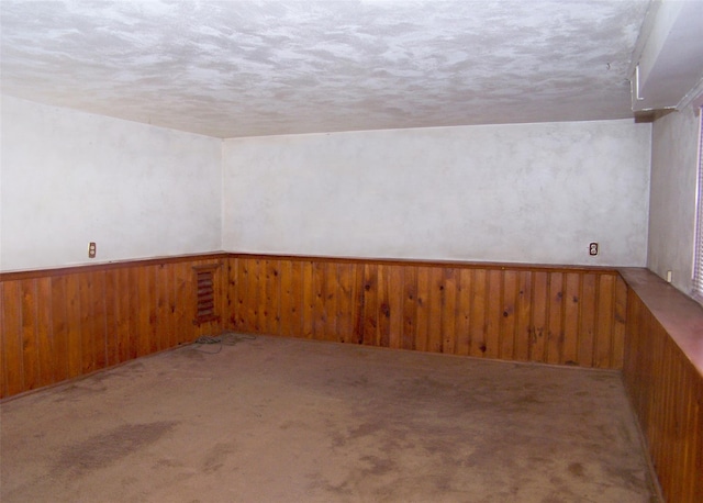 carpeted spare room with a wainscoted wall and wood walls