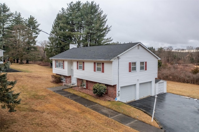 bi-level home with aphalt driveway, an attached garage, a front lawn, and roof with shingles