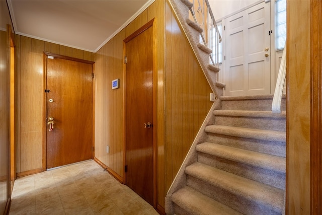 stairs with wood walls and crown molding