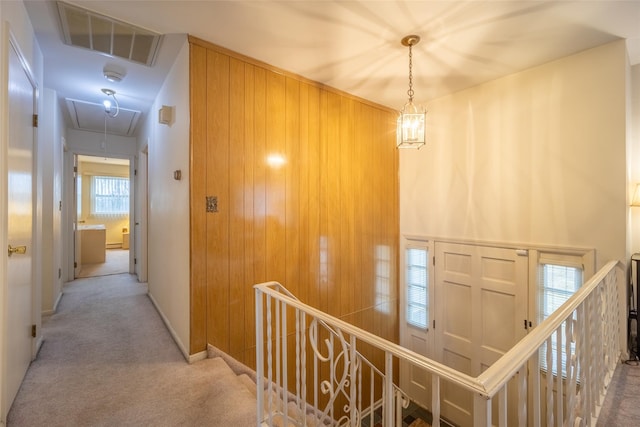 corridor featuring visible vents, baseboards, attic access, carpet flooring, and an upstairs landing