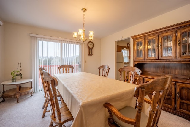 dining space with light carpet and a chandelier