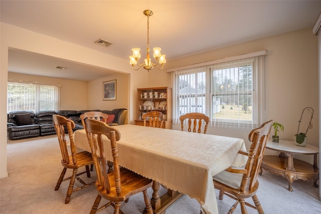 dining area with an inviting chandelier, light colored carpet, and visible vents