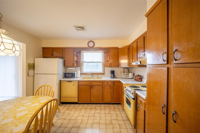 kitchen featuring white appliances, visible vents, a sink, light countertops, and under cabinet range hood