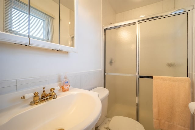 bathroom with a shower stall, toilet, wainscoting, and a sink