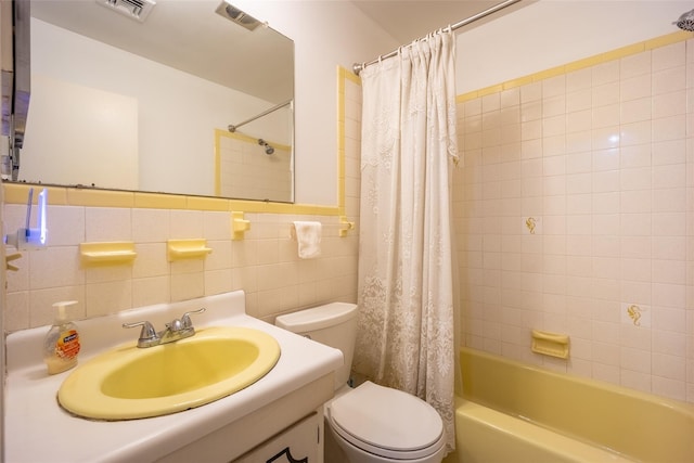 bathroom with tile walls, toilet, shower / bathtub combination with curtain, and visible vents