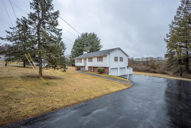 raised ranch featuring a front lawn, aphalt driveway, a garage, brick siding, and a chimney