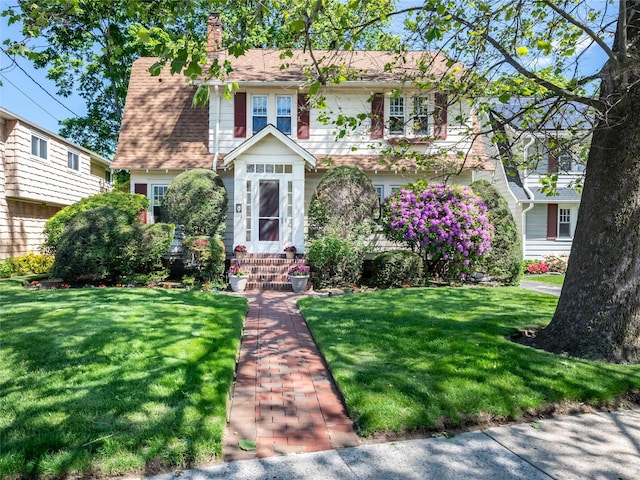 679 Saint Lukes Pl, Baldwin, NY 11510 - view of front of home with a front yard and a chimney