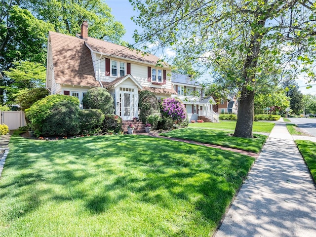 679 Saint Lukes Pl, Baldwin, NY 11510 - view of front facade featuring a chimney and a front lawn