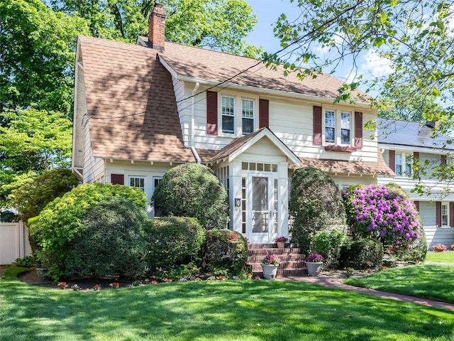 679 Saint Lukes Pl, Baldwin, NY 11510 - view of front facade with a chimney, a shingled roof, and a front lawn