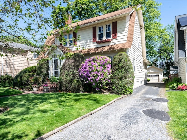 679 Saint Lukes Pl, Baldwin, NY 11510 - view of front of home with a chimney, an outbuilding, a front lawn, and a detached garage