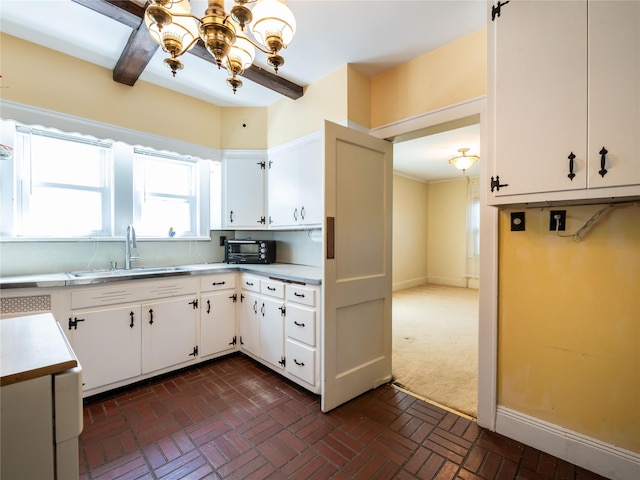 679 Saint Lukes Pl, Baldwin, NY 11510 - kitchen with a chandelier, a sink, light countertops, white cabinetry, and brick patterned flooring