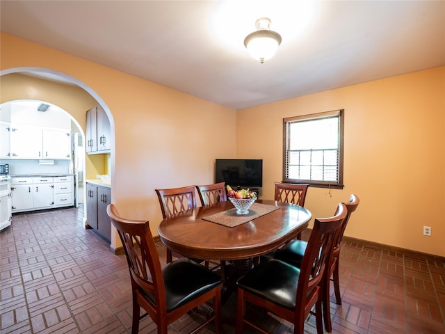 679 Saint Lukes Pl, Baldwin, NY 11510 - dining room with brick patterned floors, baseboards, and arched walkways