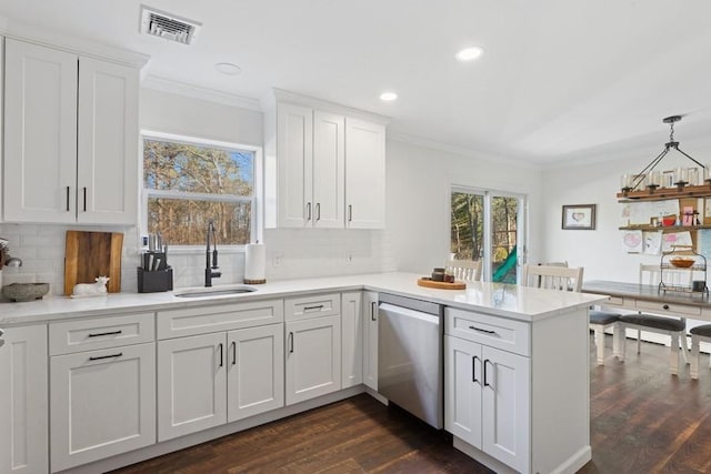 kitchen featuring visible vents, a sink, ornamental molding, a peninsula, and stainless steel dishwasher