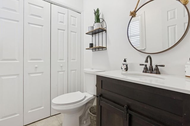 bathroom featuring a closet, tile patterned flooring, toilet, and vanity