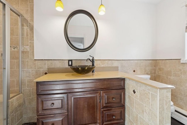 full bath with a tile shower, baseboard heating, tile walls, and vanity