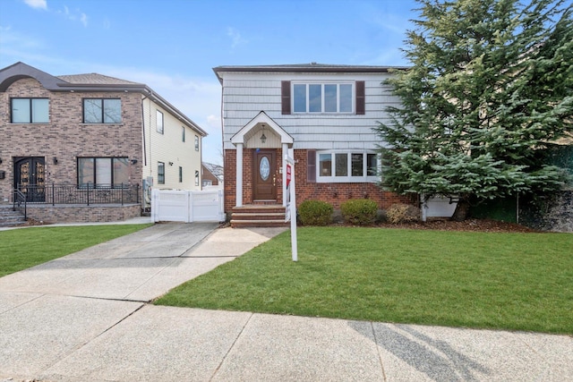 view of front of house with brick siding, a garage, a front lawn, and fence