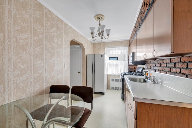 kitchen with wallpapered walls, stainless steel appliances, radiator, and a sink