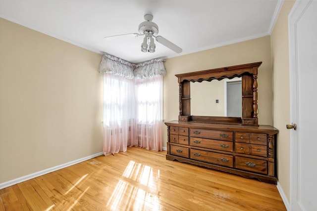 unfurnished bedroom featuring light wood-style flooring, crown molding, baseboards, and ceiling fan