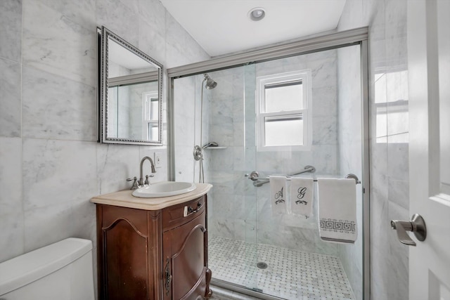 bathroom featuring toilet, tile walls, a stall shower, and vanity