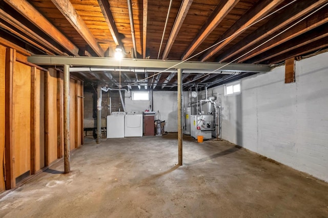 basement with a wealth of natural light, heating unit, washing machine and dryer, and water heater