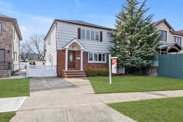 view of front facade featuring a gate, fence, concrete driveway, a front yard, and brick siding