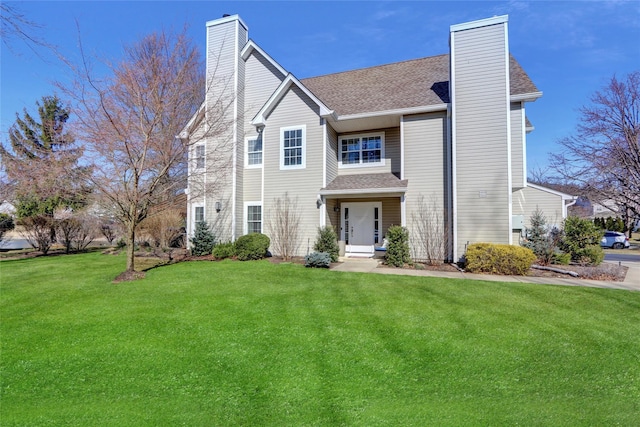 view of front facade featuring a shingled roof, a front lawn, and a chimney