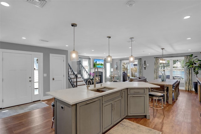 kitchen featuring visible vents, light wood-style flooring, gray cabinetry, light countertops, and a kitchen breakfast bar