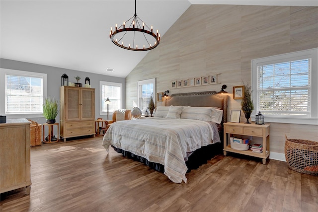 bedroom with an inviting chandelier, wood finished floors, visible vents, and high vaulted ceiling