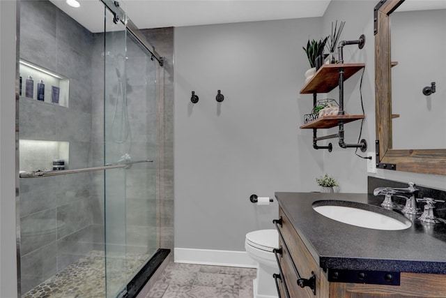 bathroom featuring vanity, toilet, baseboards, and a stall shower