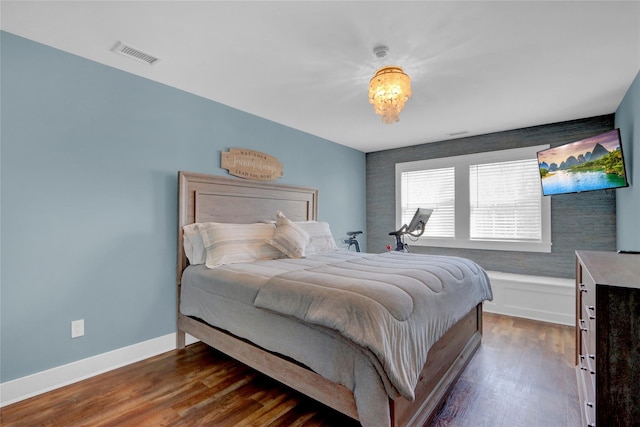 bedroom featuring visible vents, baseboards, and wood finished floors